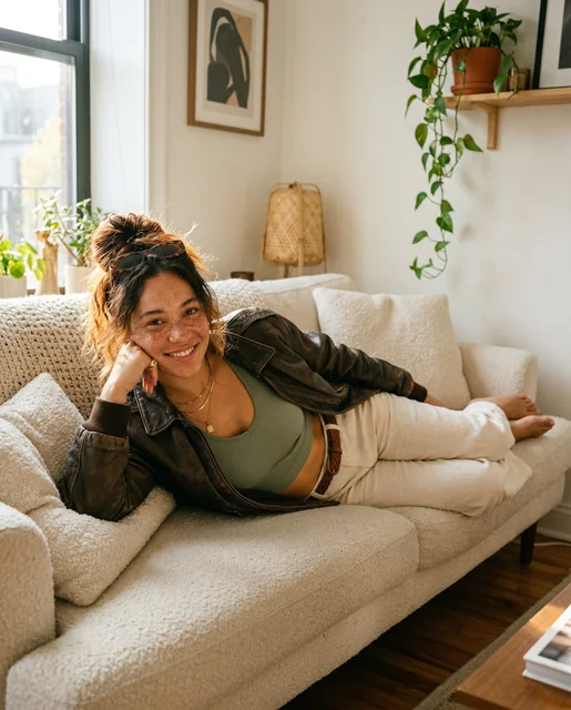 American mixed heritage woman on Brooklyn boucle sofa - leather bomber freckles golden light