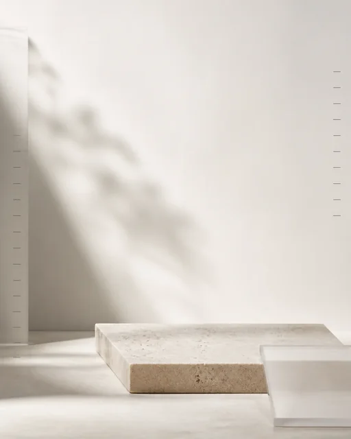 Empty neutral ecommerce product-inspection set with limestone plinth, frosted acrylic, soft side light, and measurement ticks